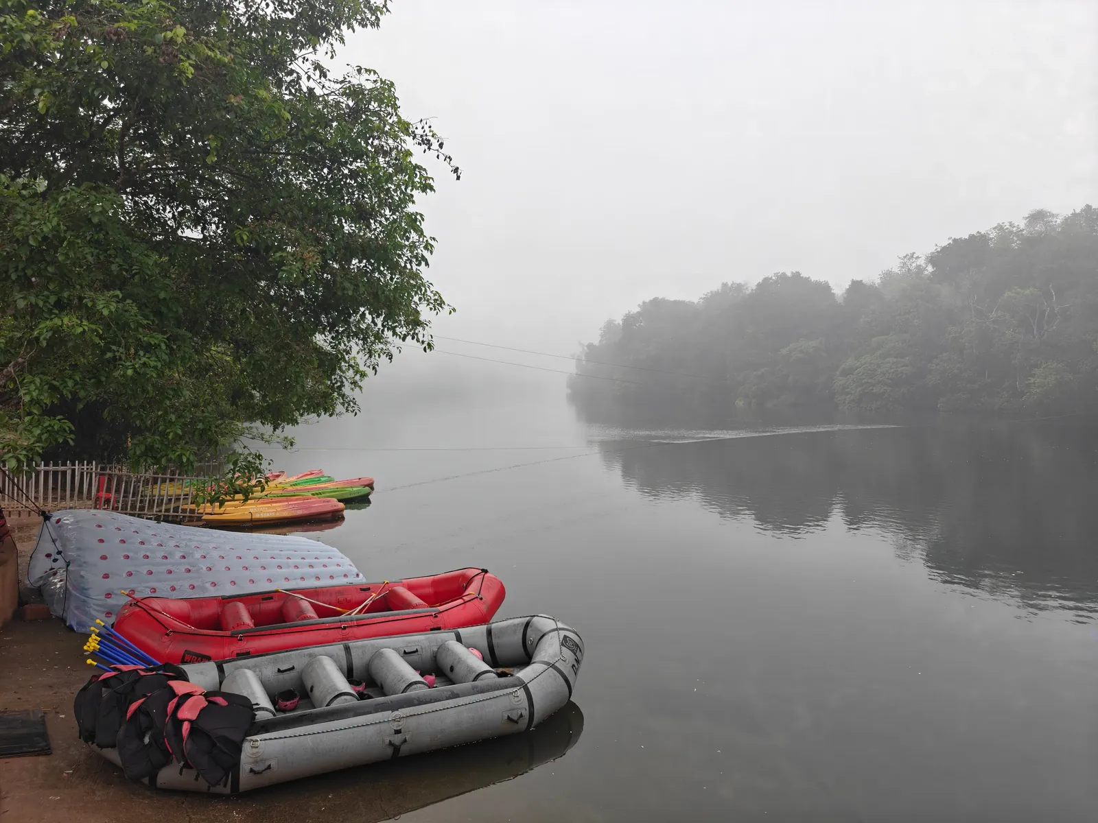 Calm misty Kali River with rafts on the bank at dawn